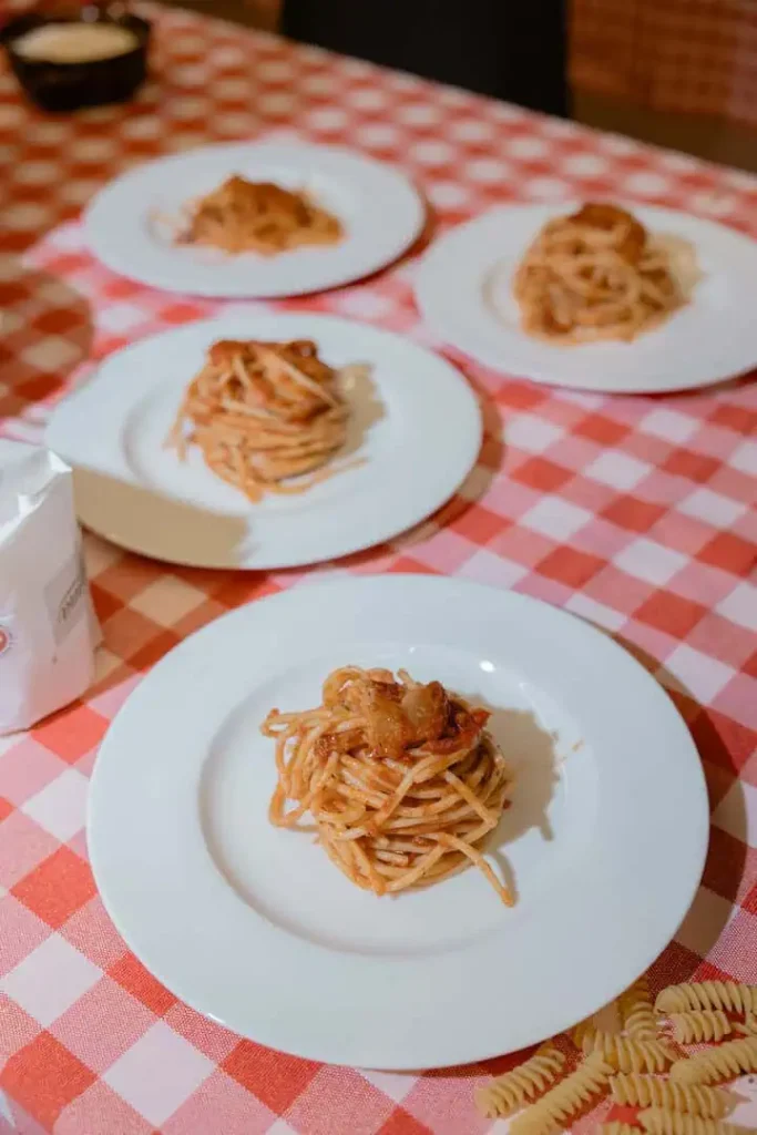 Spaghetti with tomato souce displayed in a table with red and white checkered tablecloth