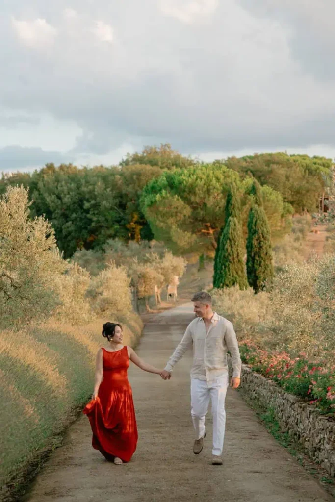 Bride in red and groom in white walking hand in hand towards the Welcome Party